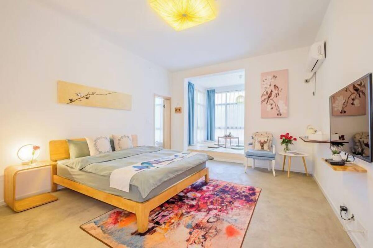 A modern bedroom with a bed, bedside table, and a large window.