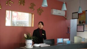 A reception desk with a red wall, a potted plant, and a nameplate.