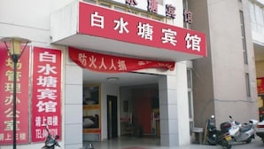 A hotel entrance with a red signboard and a smaller sign below it.