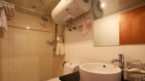 A bathroom with a toilet, sink, and shower. There are towels hanging on the wall and a mirror above the sink.