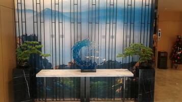 A reception area with a reception desk, a decorative wall with vertical lines, and two potted plants.