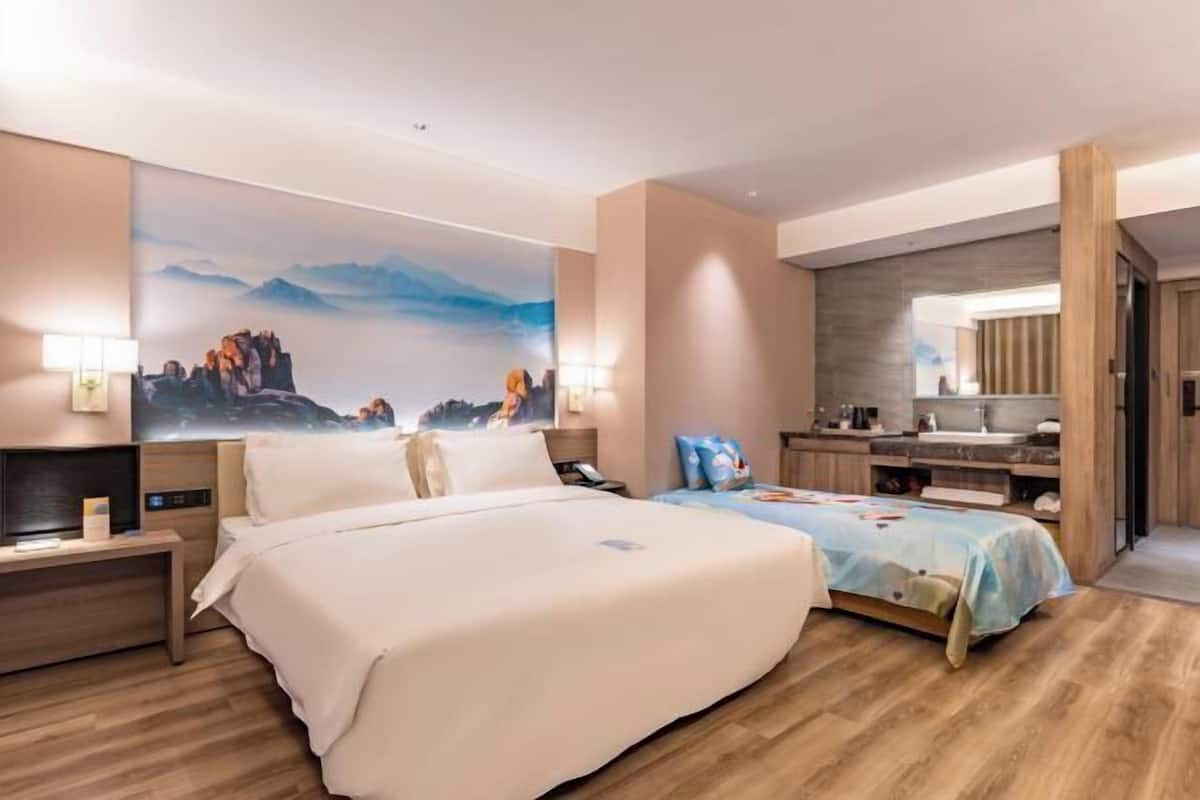 A hotel room with a large bed, bedside tables, a desk, a mirror, and a bathroom with a sink and mirror.