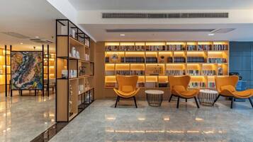 A modern library with bookshelves, a large painting, and comfortable seating.