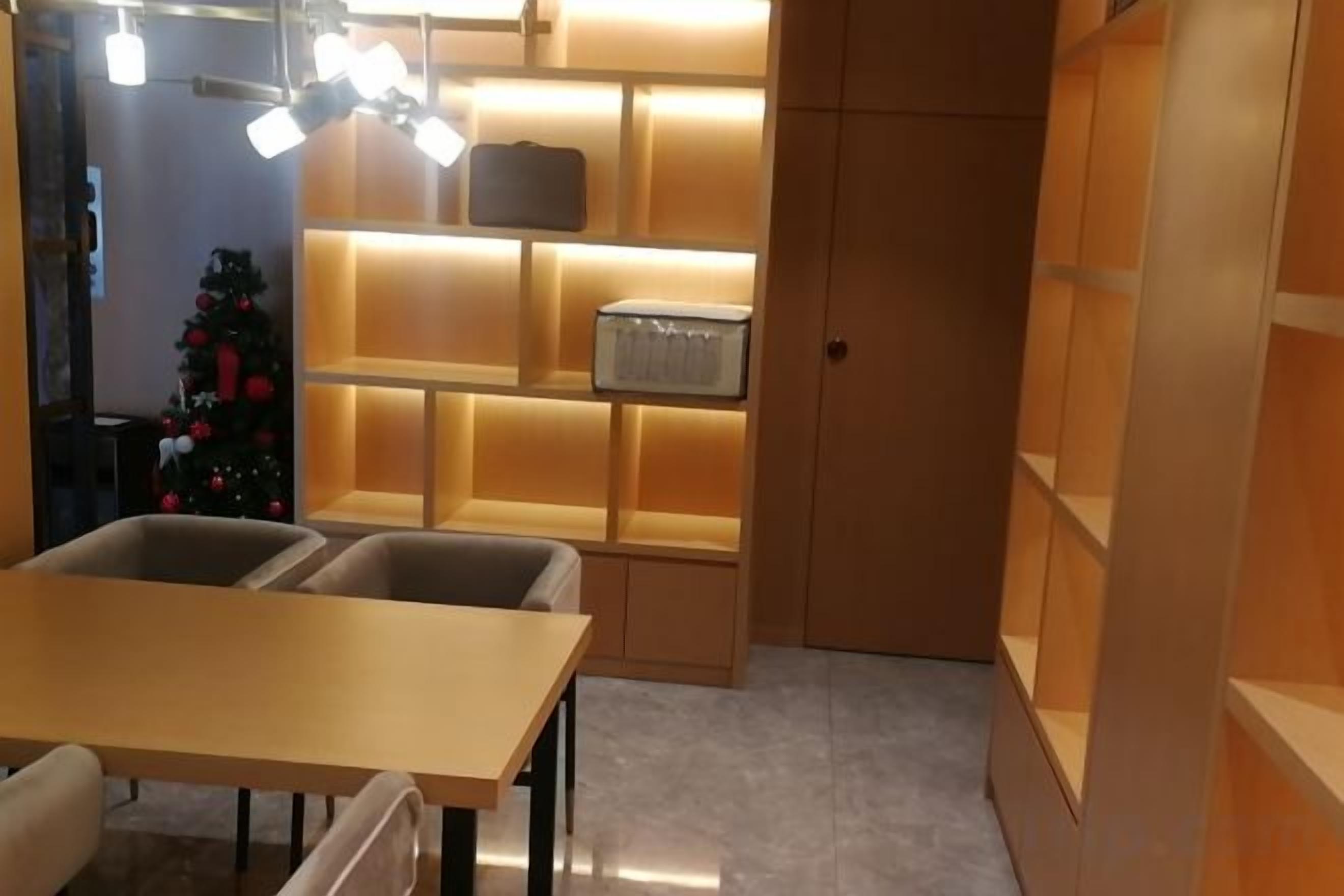 A room with a table, chairs, a Christmas tree, and shelves with illuminated boxes.