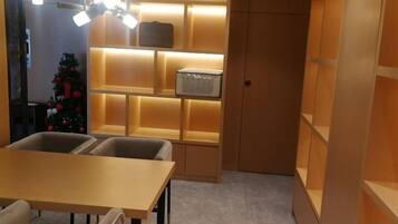 A room with a table, chairs, a Christmas tree, and shelves with illuminated boxes.