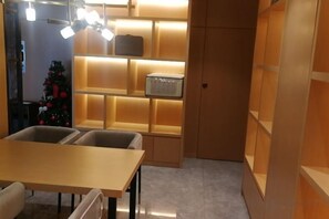 Quarto com mesa, cadeiras, árvore de Natal e prateleiras com caixas iluminadas.
