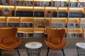 A library with bookshelves and two orange chairs. - Hotel of The Future (Jiefang Road) (Wulian)