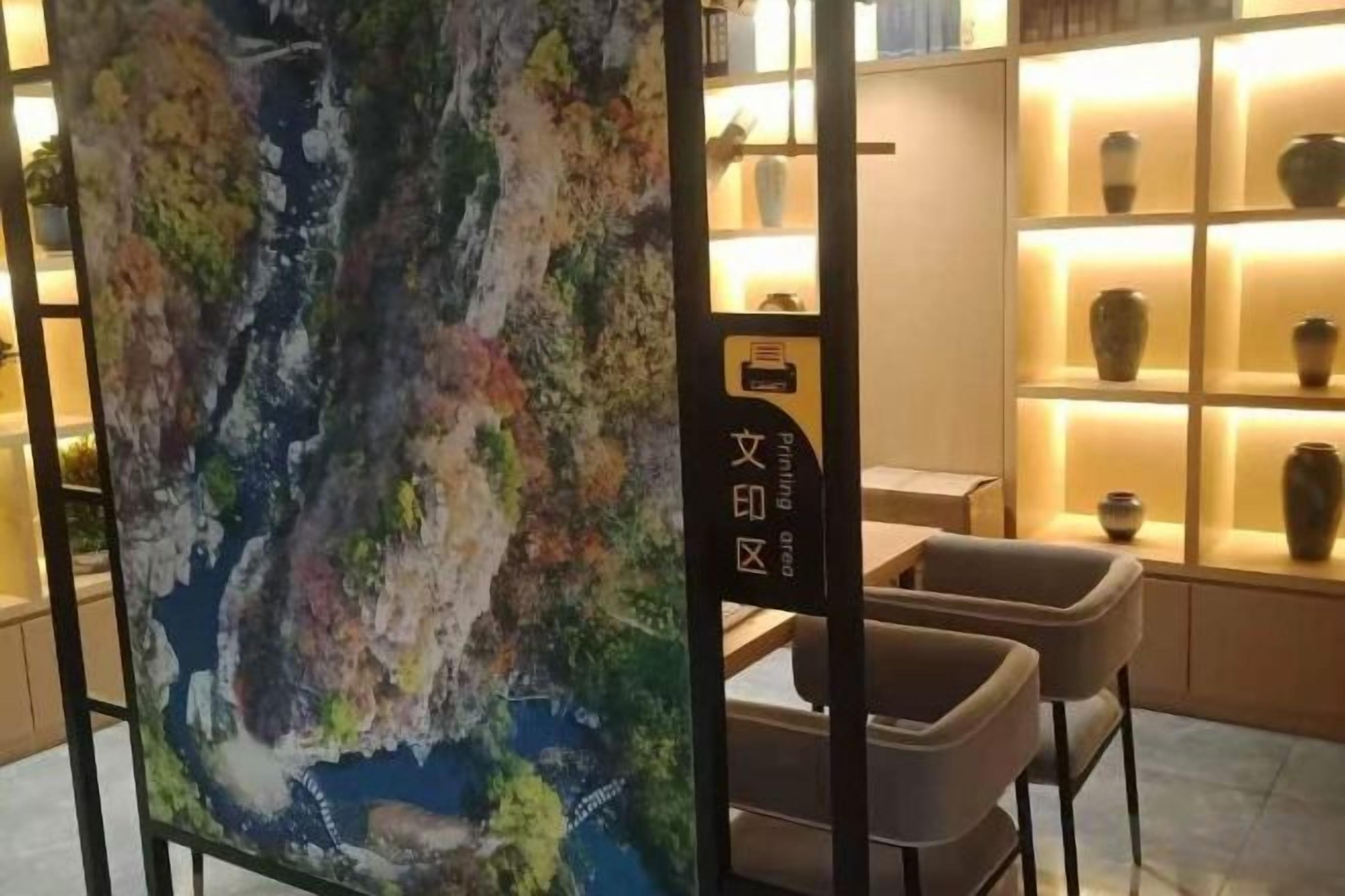A room with a large abstract painting, a desk, and shelves with pottery.