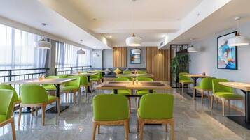 A modern dining area with tables and chairs, large windows, and a view of the outdoors.