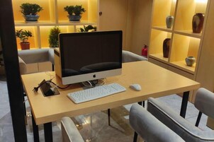 Un escritorio con monitor de computadora, teclado y ratón, rodeado de sillas.