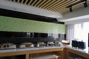 Una cocina moderna con encimera negra, salpicadero verde y ventana con cortinas.