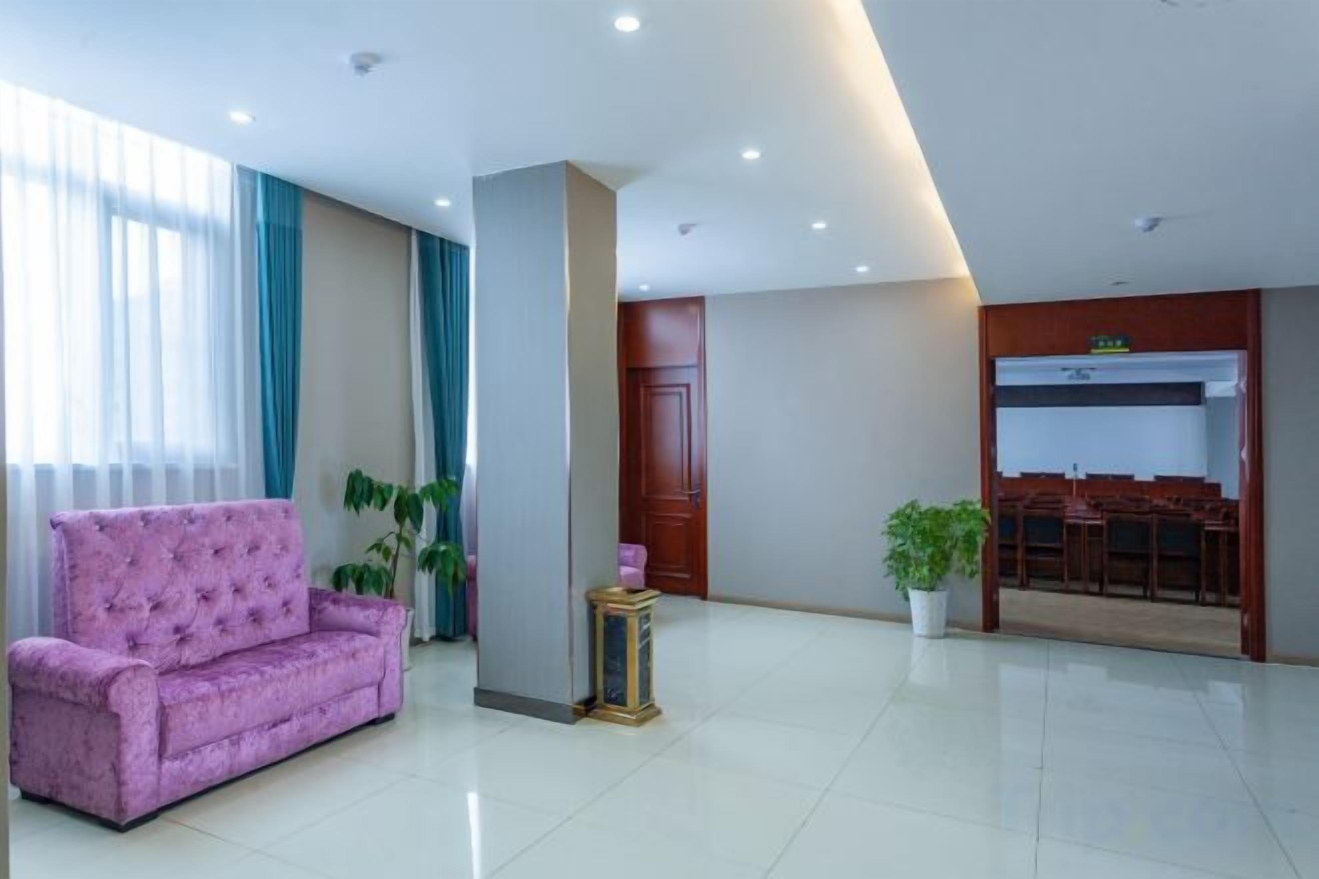 A hotel lobby with a pink sofa, a potted plant, and a reception desk.