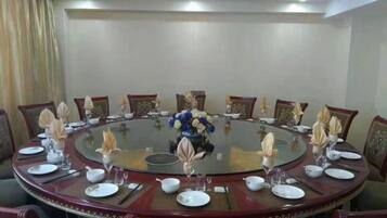 A conference room with a round table, chairs, and a central floral arrangement.
