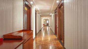 A hotel hallway with a reception desk, doors, and a marble floor.