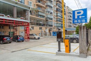 A parking area with a blue sign indicating a parking lot, surrounded by multi-story residential buildings. - New Beacon International Hotel (Luotian Tashanhu Park) (Luotian County)
