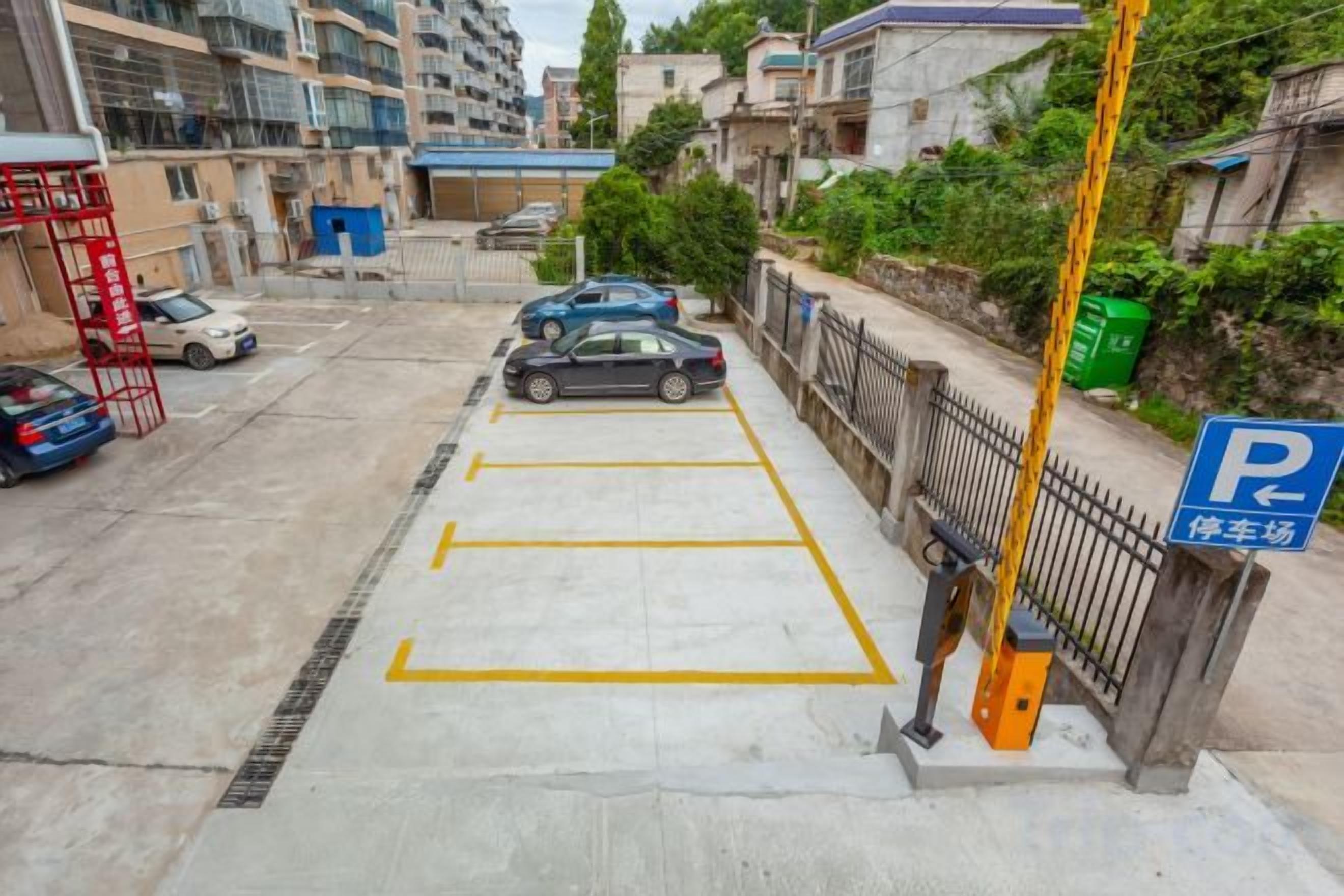 A parking area with marked spaces, a blue parking sign, and a yellow pole.