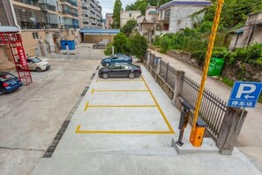 Une zone de stationnement avec des emplacements délimités, un panneau de signalisation bleu indiquant les places de stationnement, et un poteau jaune.