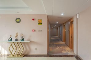 A hotel hallway with a reception desk, a fire alarm, and a no-smoking sign. - New Beacon International Hotel (Luotian Tashanhu Park) (Luotian County)