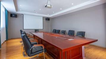 A conference room with a long table, chairs, a projector screen, and a whiteboard.