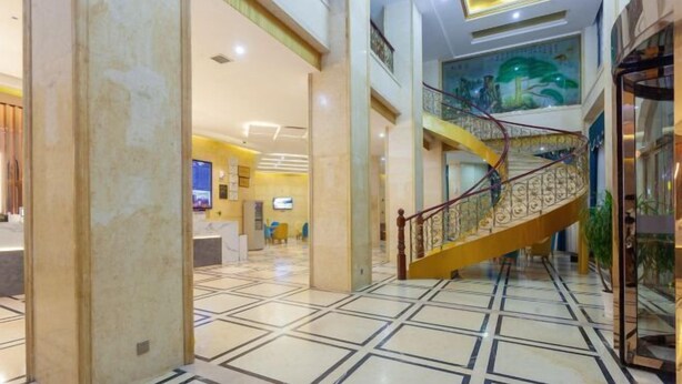 A spacious lobby with a marble floor, a curved staircase, and a reception area. - New Beacon International Hotel (Luotian Tashanhu Park) (Luotian County)