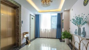 A hotel lobby with a marble floor, a reception desk, a potted plant, and a chandelier. - New Beacon International Hotel (Luotian Tashanhu Park) (Luotian County)