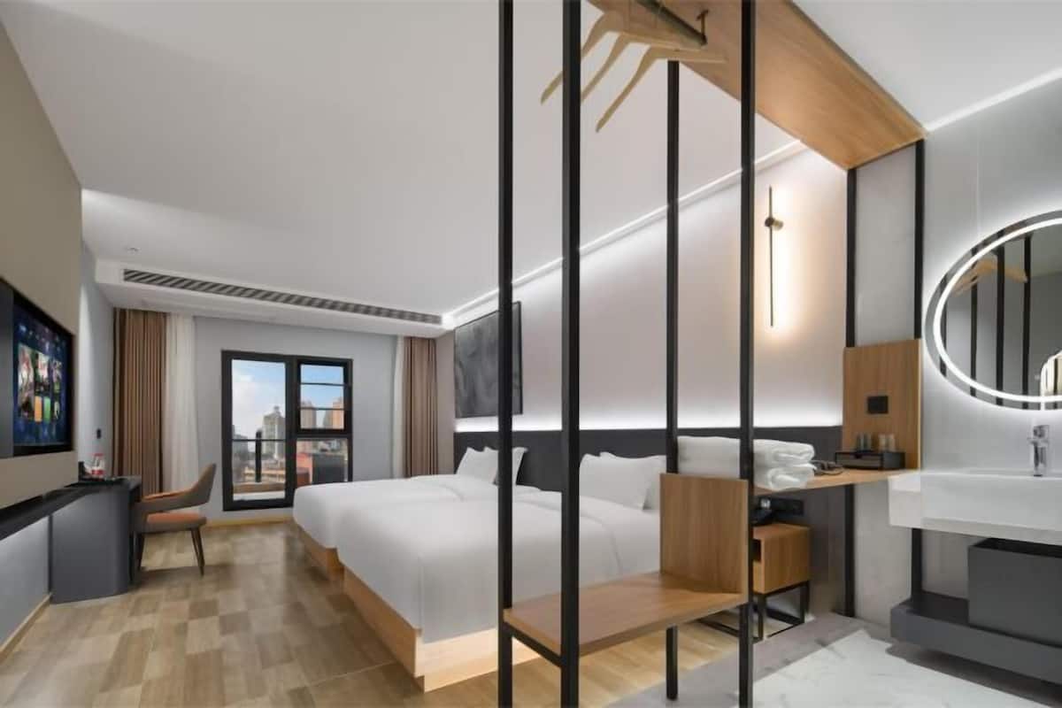 A modern hotel room with a bed, desk, and bathroom.