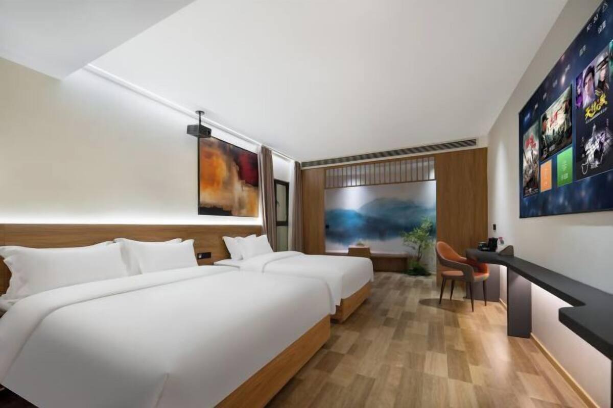 A hotel room with two beds, a desk, and a large window with a view.