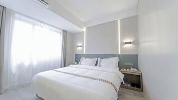 Una habitación de hotel con una cama grande, mesitas de noche, un ventanal con cortinas y un equipo de aire acondicionado.