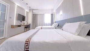 A hotel room with two beds, a desk, a chair, and a TV.