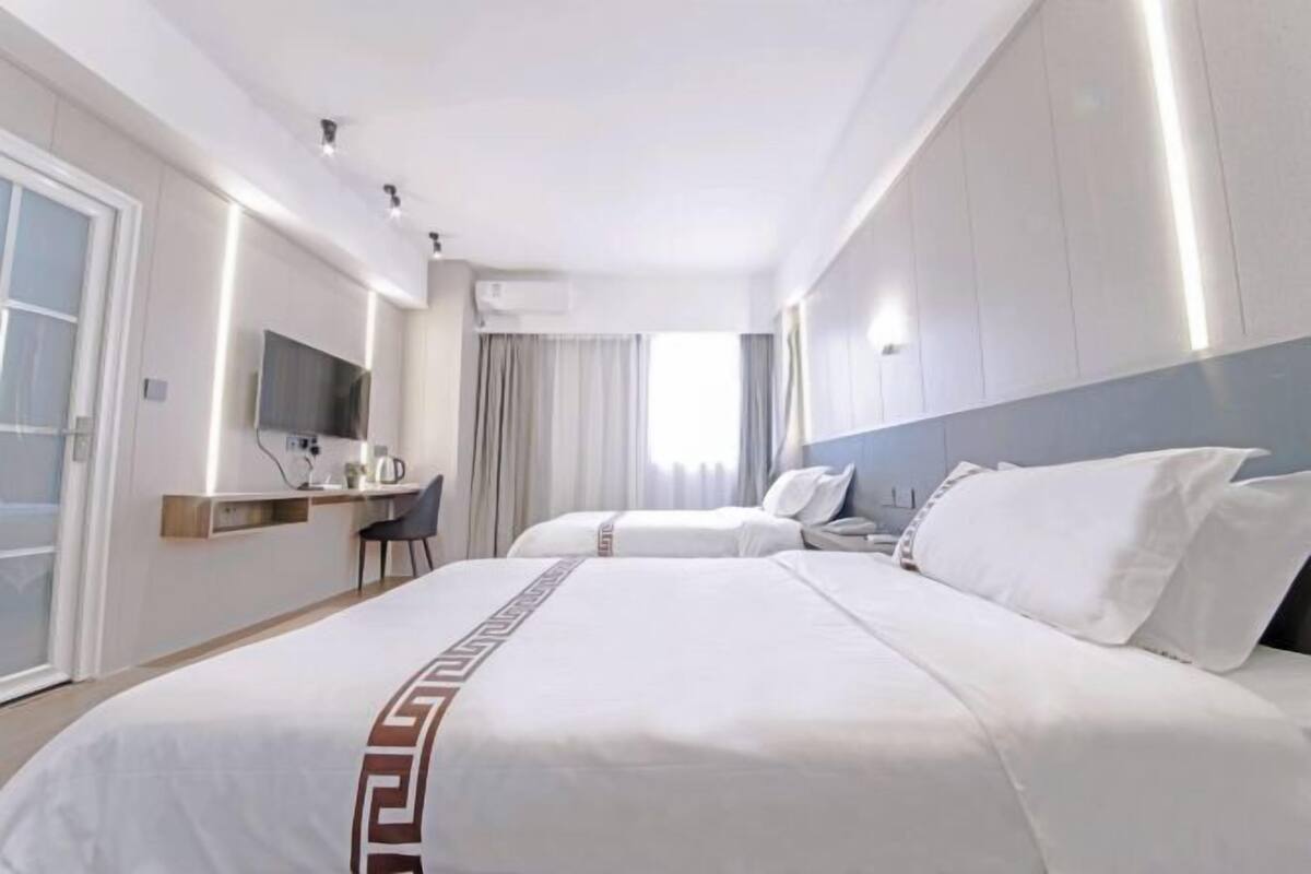 Une chambre d’hôtel avec deux lits, un bureau, une chaise et un téléviseur.
