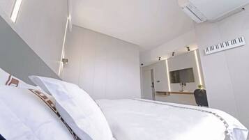 Una habitación de hotel con una cama, un escritorio, una silla, un espejo y una ventana.