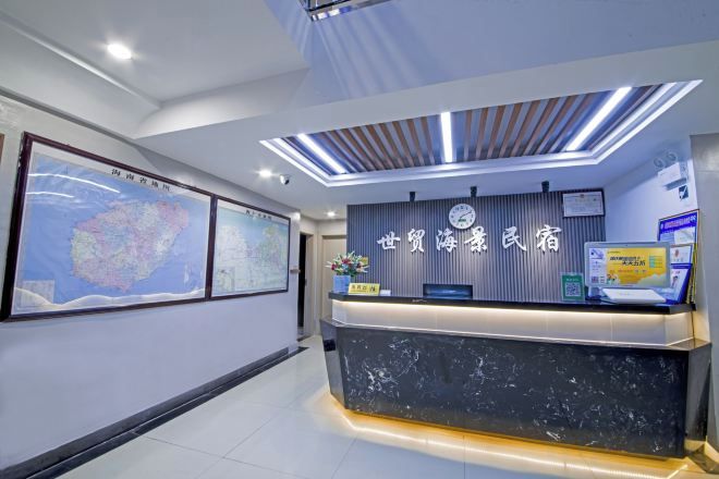 Un mostrador de recepción con una pantalla digital, mapas enmarcados y un reloj.