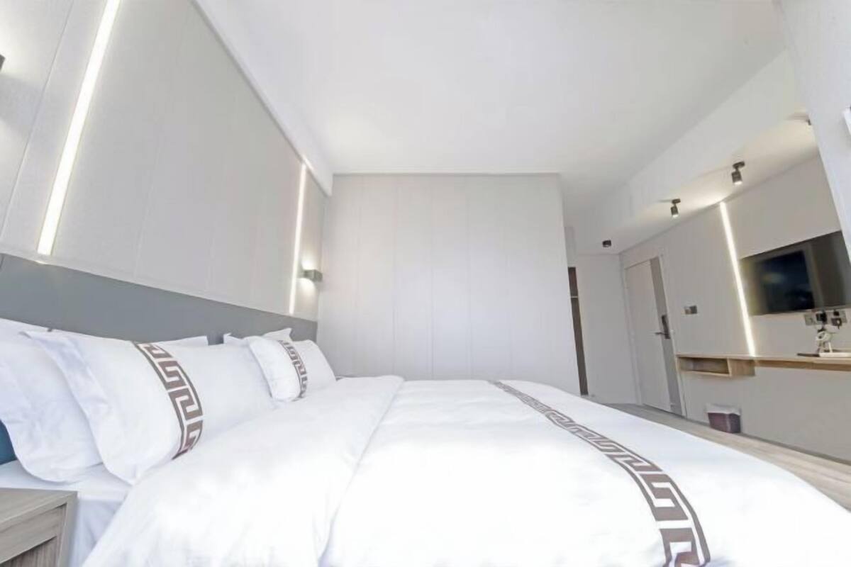 Une chambre d’hôtel moderne dotée d’un grand lit, d’une table de chevet, d’un miroir et d’un téléviseur intégré.