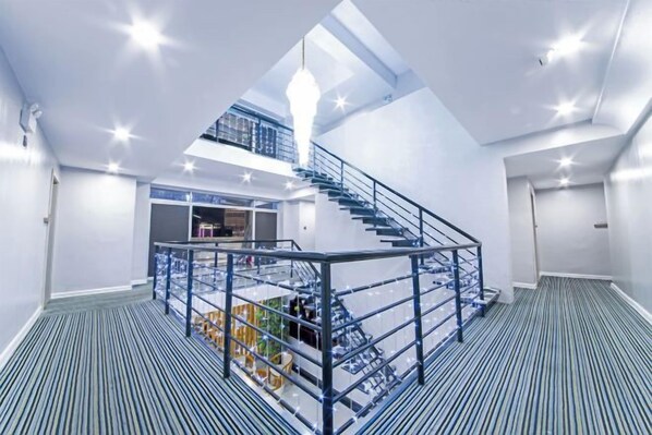 Un interior espacioso con una escalera central, un entrepiso y vistas a la ciudad.