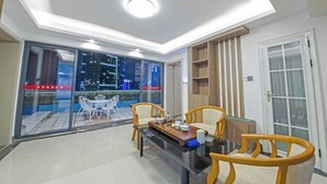 A modern dining area with a glass table and wooden chairs, a ceiling light, and a view of the outside.