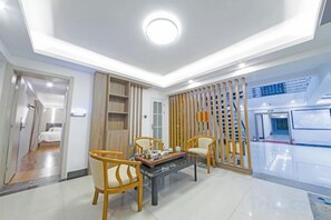 A modern hotel room with a dining area, a wooden partition, and a view of the city. - Shimao Haijing Guesthouse (Haikou)