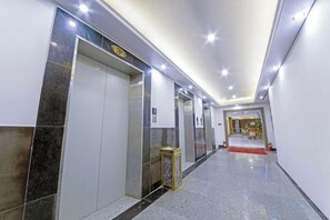 A hotel corridor with elevators, a reception area, and a red carpet leading to a door. - Shimao Haijing Guesthouse (Haikou)