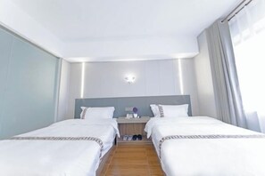 A hotel room with two beds, a nightstand, a lamp, and a window with curtains. - Shimao Haijing Guesthouse (Haikou)