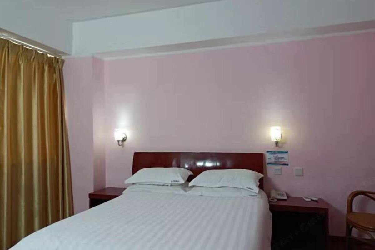 Une chambre d’hôtel comprenant un lit, deux tables de chevet, une chaise et un téléphone fixé au mur.