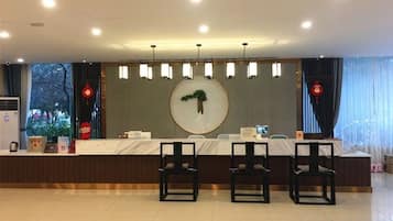 A hotel reception area with a marble counter, two black chairs, and a round wall decoration.