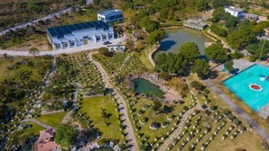 An aerial view of a resort with a large building, a swimming pool, and landscaped gardens. - Green Field Manor (Ningbo)