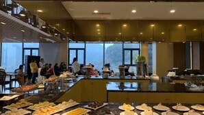 A buffet area with various food items and a group of people gathered around. - Green Field Manor (Ningbo)