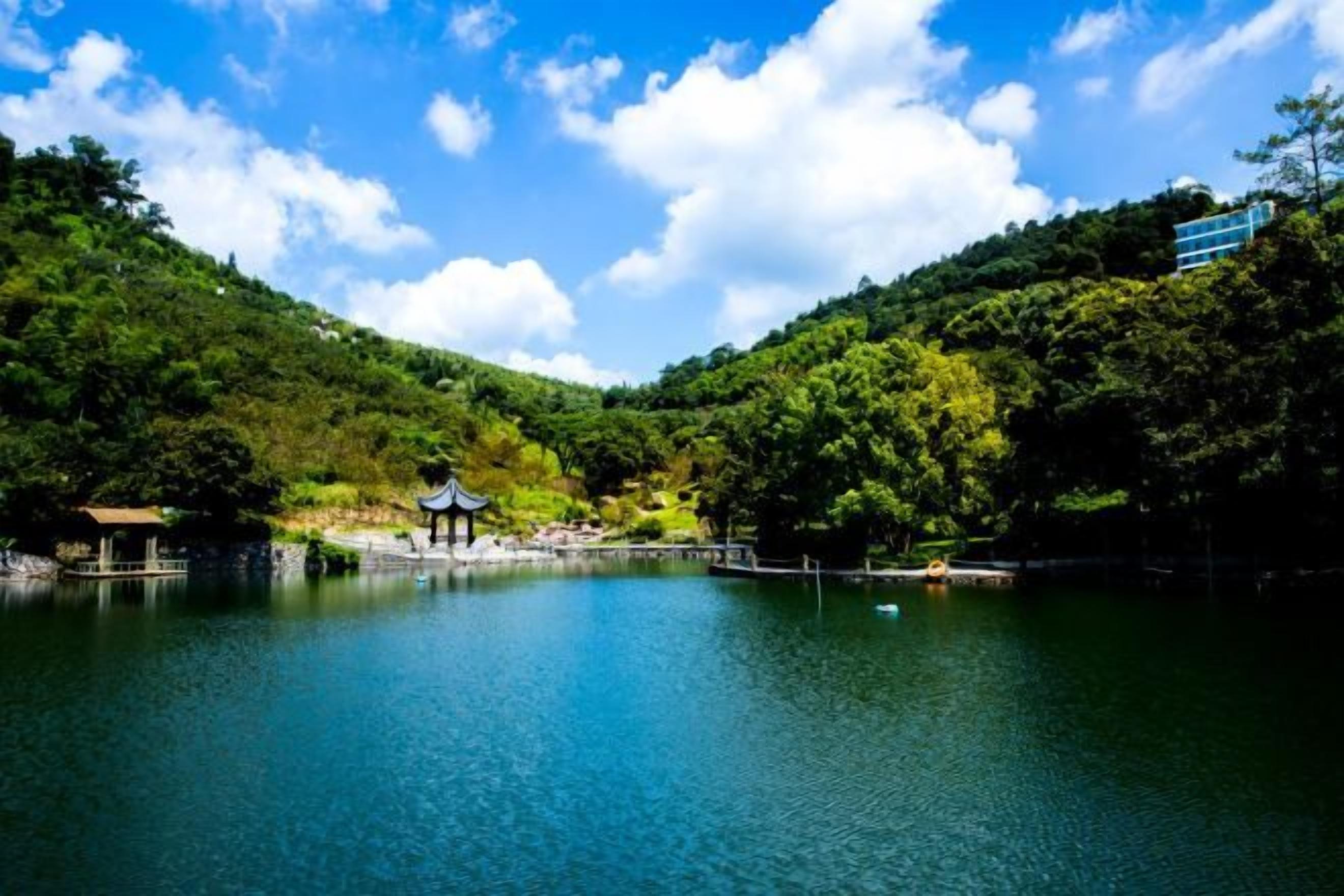 A serene lake surrounded by lush greenery, a gazebo, and a pavilion.