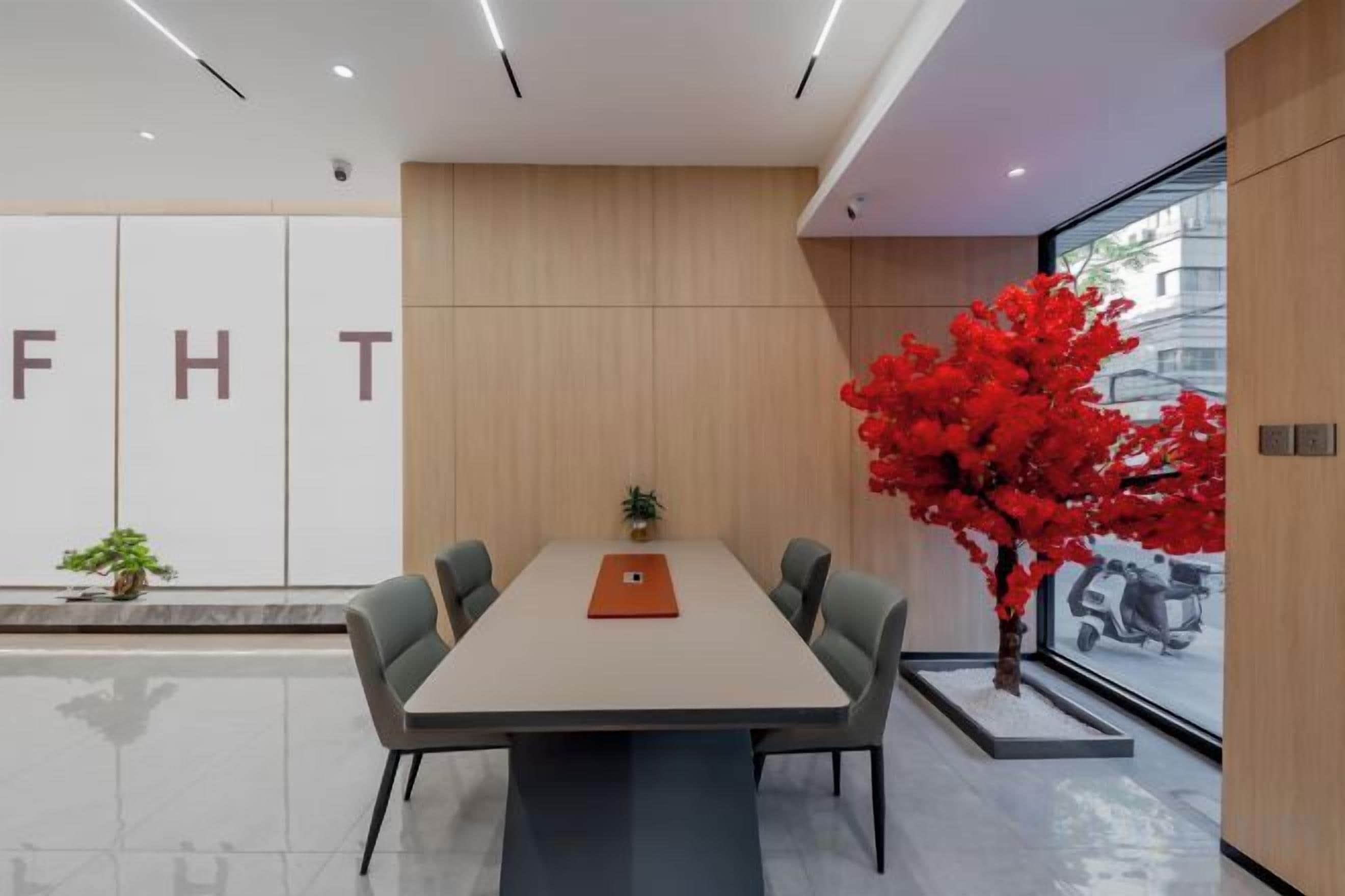Une salle de conférence moderne, dotée d’une longue table, de quatre chaises et d’une plante en pot.
