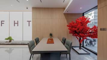 Una sala de conferencias moderna con una larga mesa, cuatro sillas y una planta en maceta.