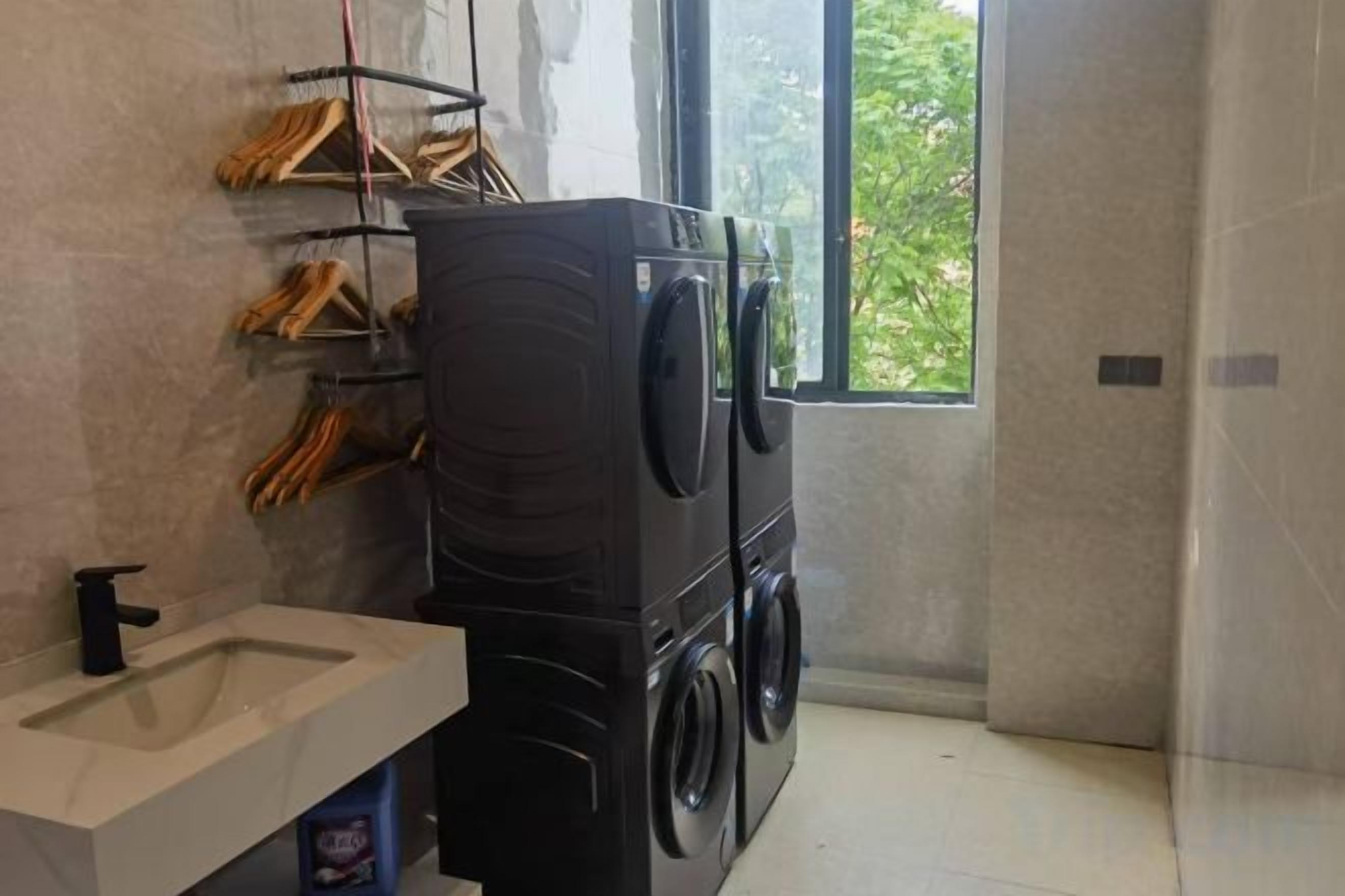 A compact laundry area with a washing machine and dryer, a sink, and a window providing natural light.