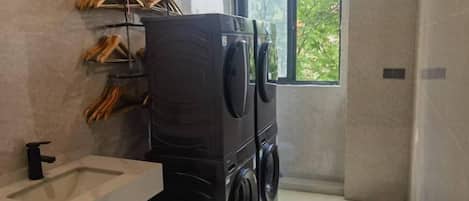 A compact laundry area with a washing machine and dryer, a sink, and a window providing natural light.