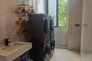 A compact laundry area with a washing machine and dryer, a sink, and a window providing natural light. - YUE FEI YUN Hotel (Shanghai)