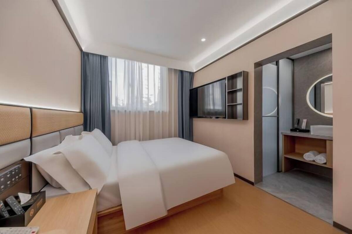 Une chambre d’hôtel comprenant un lit, un bureau avec un téléphone, une télévision et un miroir.