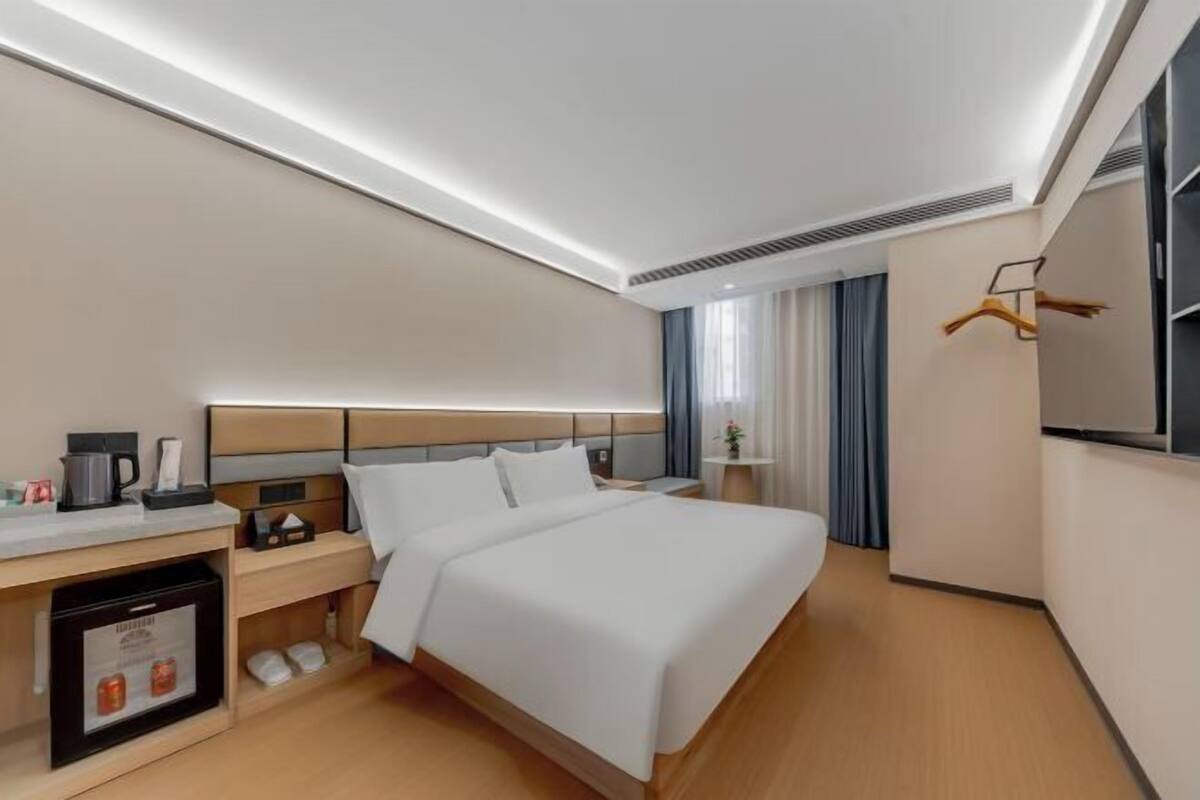 Une chambre d’hôtel moderne avec un grand lit, une table de chevet et un petit coin cuisine.